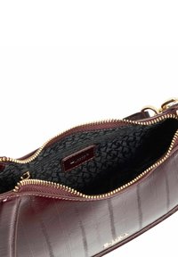 Burgundy leather bag with a textured finish and gold zipper. Interior features a patterned fabric lining and a brand label.