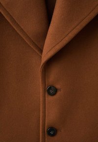 Abrigo de lana marrón con cuello de muesca, que presenta dos botones negros. Textura suave con costuras limpias a lo largo de los bordes.