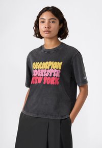 Czarny bawełniany t-shirt z krótkim rękawem, z dużym, retro-stylowym nadrukiem w kolorze żółtym, różowym i czerwonym: "Champion Rochester New York."