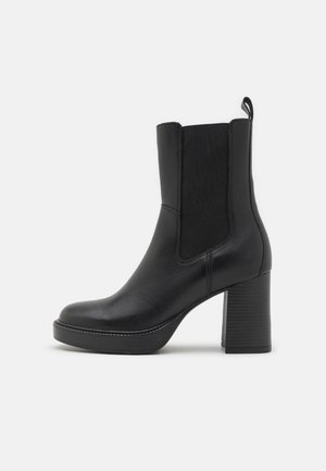 Black leather ankle boot with a rounded toe, elastic side panels, and a ribbed high heel. Smooth texture with minimal stitching details.