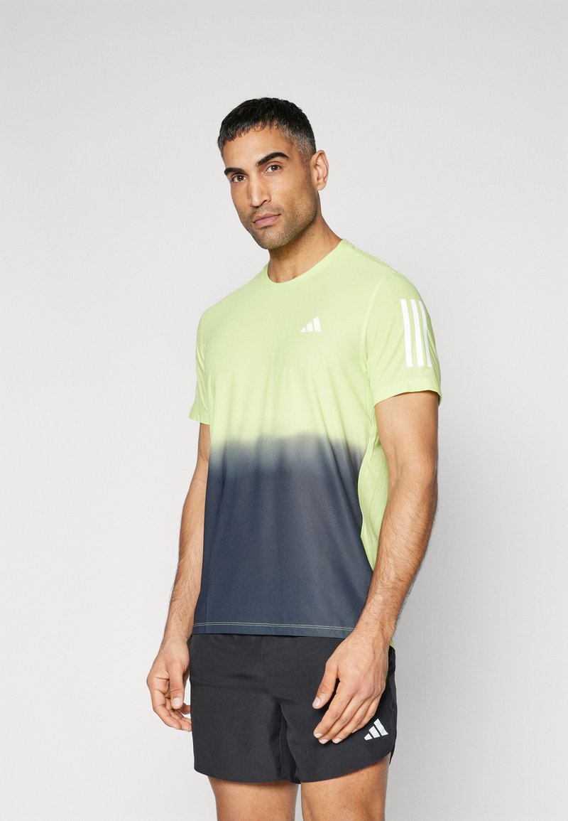 Camisa atlética de manga corta para hombre, con un degradado de verde fluorescente a azul marino, con tres franjas blancas en el hombro izquierdo y un logo en el pecho.