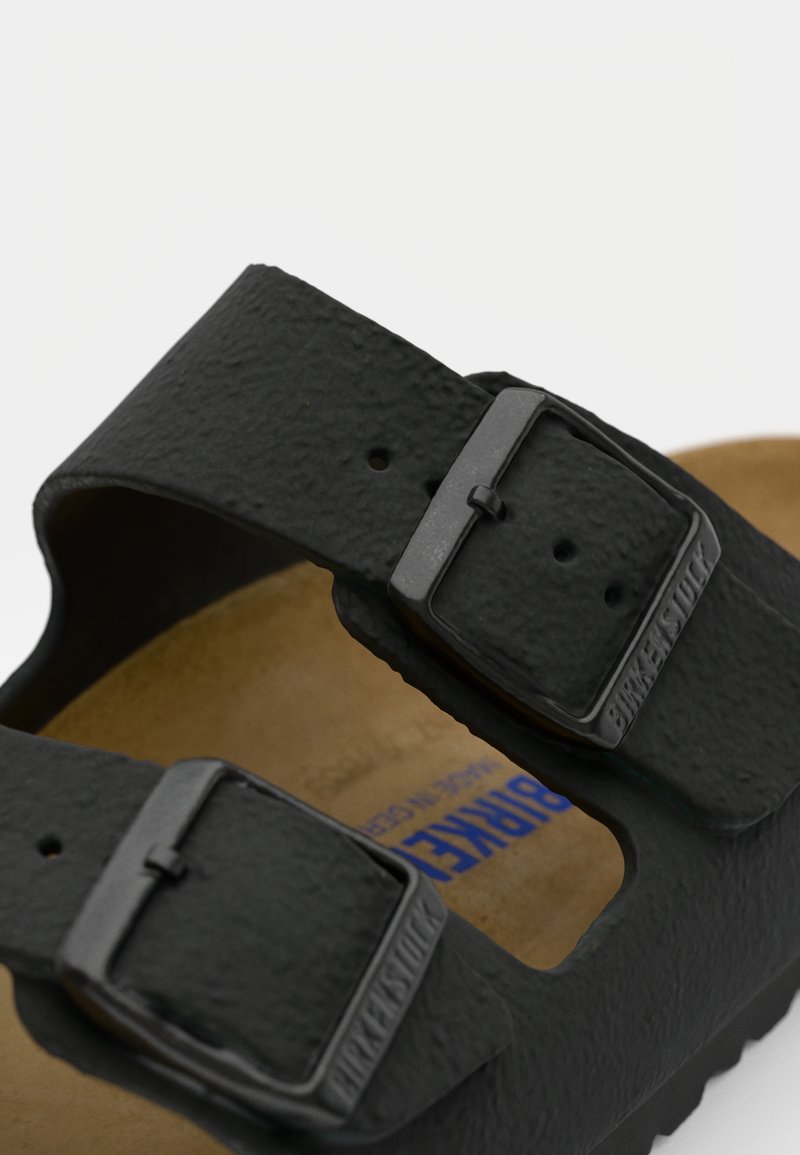Schwarze Birkenstock-Sandalen mit zwei strukturierten Riemen, verstellbaren Schnallen und einem Korkfußbett mit brauner Oberfläche.