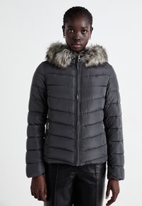 Giacca a vento grigia con cappuccio in pelliccia sintetica, dotata di zip frontale, texture trapuntata e tasche laterali. Completata da una silhouette aderente.