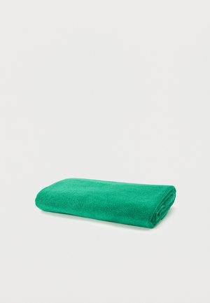 Serviette en microfibre verte éclatante, pliée et étalée à plat sur une surface blanche.