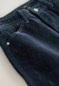 Pantaloni de culoare albastru marin din catifea, cu cusături de culoare albastru deschis, accesorii din metal argintiu, design cu cinci buzunare și textură moale.