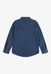 Camicia di denim, blu scuro, maniche lunghe, colletto a punta, orlo curvo, polsini con un solo bottone e dettagli di cucitura sottili sul retro.