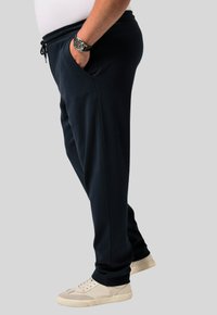 Marinblåa mjukiska med elastisk midja och dragsko, med sidofickor och en avslappnad passform, tillsammans med off-white sneakers.