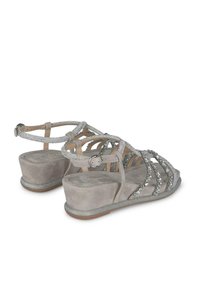 Sandali wedge in suede grigia con accenti metallici argento e decorazioni in strass. Presentano un design a più cinturini e chiusura con fibbia alla caviglia.