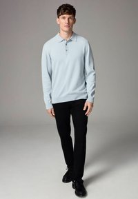 Svetlomodrá polo košeľa s dlhým rukávom a jemnou textúrou, trojbuttonová léga a rebrované manžety, doplnená o čierne slim-fit nohavice a čierne topánky.