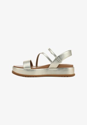 Sandales métalliques argentées avec deux larges brides, une bride arrière et une semelle épaisse beige avec un motif antidérapant texturé.