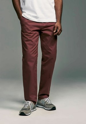 Chino color amaranto realizzati in tessuto misto cotone, con una vestibilità su misura e tasche laterali. Abbinati a sneakers grigie New Balance.