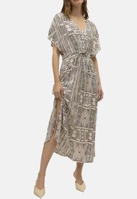 Beige maxi dress with black geometric pattern, V-neck, short sleeves, gathered waist, and side slits for easy movement.