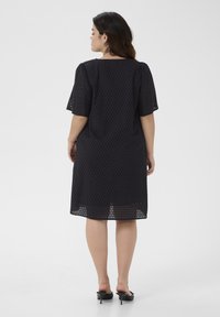 Black, short-sleeved dress with eyelet detailing and a relaxed fit, featuring a straight hem and mid-length silhouette.
