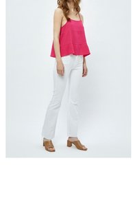 Fuchsia ärmlös topp med horisontella sömmar, kombinerad med figurnära vita byxor och sandaler med blockklack i beige. Enkelt, avslappnat snitt.