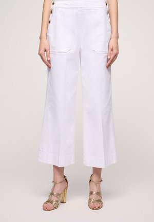 Pantaloni bianchi a gamba larga con tasche laterali e dettagli in bottone dorato, caratterizzati da una texture di cotone liscia e un design cropped e sartoriale.
