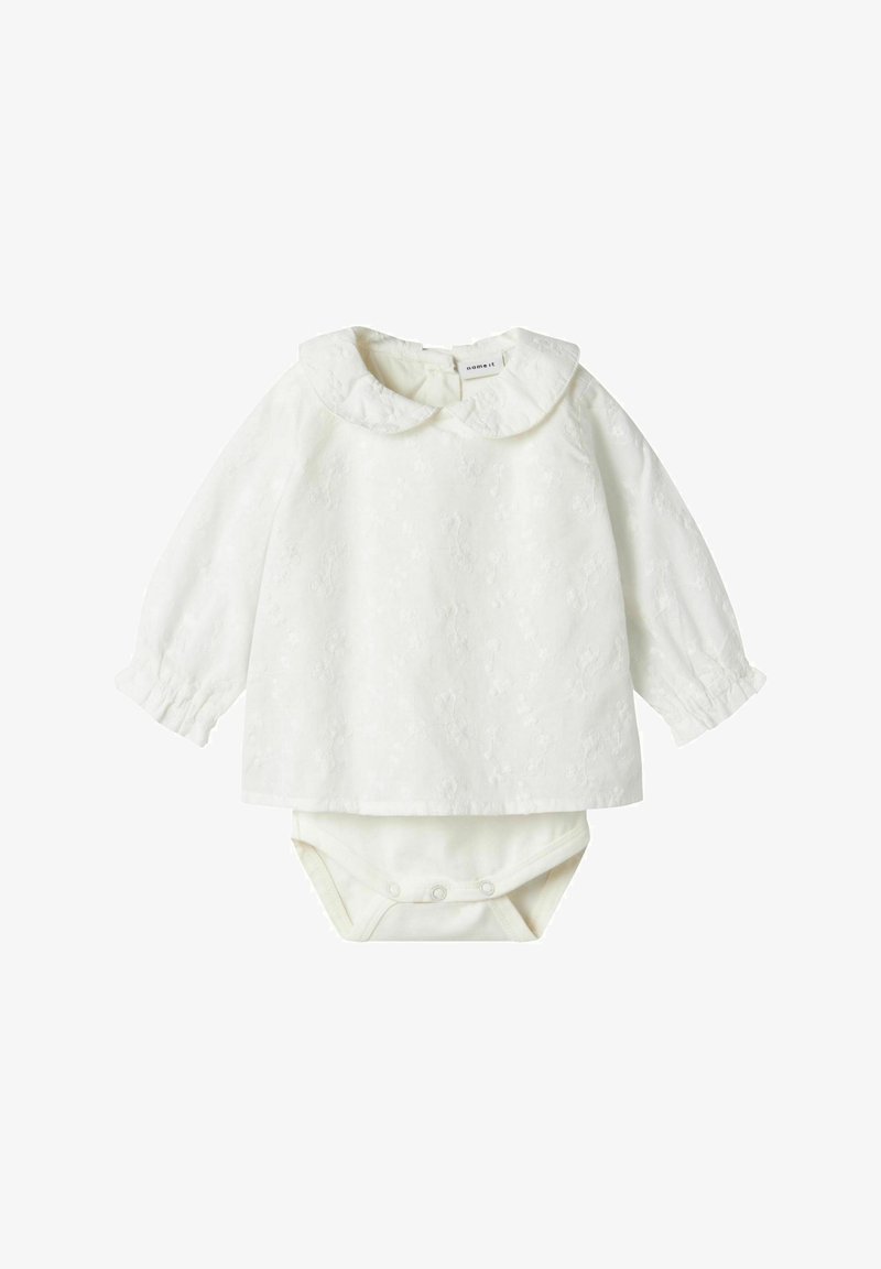 Maglietta bianca a maniche lunghe con colletto arrotondato e motivo floreale a rilievo, abbinata a un body coordinato con chiusure a pressione.