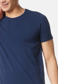 Marinblå bomull T-shirt med korta ärmar och rund halsringning. Mjuk textur, figurnära design, minimal sömdetaljer.