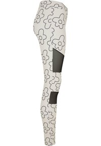 Hvite leggings med svart blomsterdesign, med et mesh-panel på siden. Laget av stretchmateriale, kroppsnær passform.