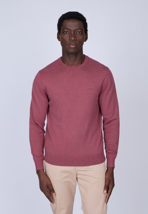 Pull ras du cou dans une teinte rose-rouge, en tissu tricoté, à manches longues, avec des bords-côtes aux poignets et à l'ourlet, arborant un petit logo sur la poitrine.