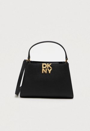 Sac à main structuré noir avec poignée supérieure, bandoulière détachable et logo DKNY doré à l'avant sur un fond clair uni.