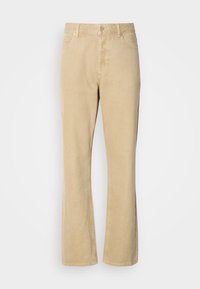Pantalons en velours côtelé beige évasés avec une fermeture à bouton et à fermeture éclair, comportant cinq poches et des coutures visibles le long des jambes. Texture lisse.