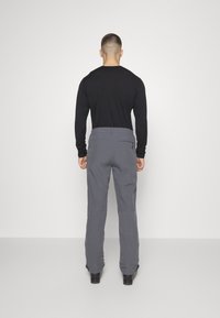 Szare spodnie o kroju dopasowanym, z gładką fakturą, tylnymi kieszeniami i zamkiem. Połączone z dopasowanym czarnym topem z długim rękawem.