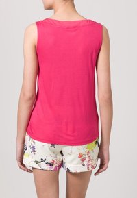 Mouwloos roze topje van een zachte stof, met een ontspannen pasvorm en ronde halslijn, gecombineerd met bloemenpatroon shorts in zachte kleuren.