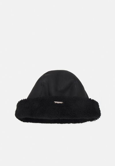 Chapeau en cuir noir avec un revers en fourrure noire douce et texturée, ainsi qu'un accent métallique à l'avant. Design de sommet concave avec un ajustement snug.