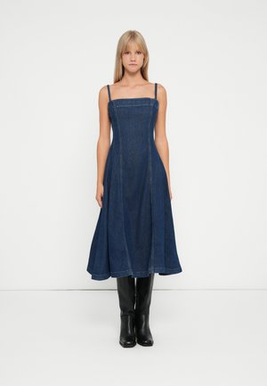 Denim A-linje kjole med firkantet halsringning, tynne stropper og sømdetaljer. Fargen er mørkeblå; stoffet ser glatt ut med en lett tekstur.