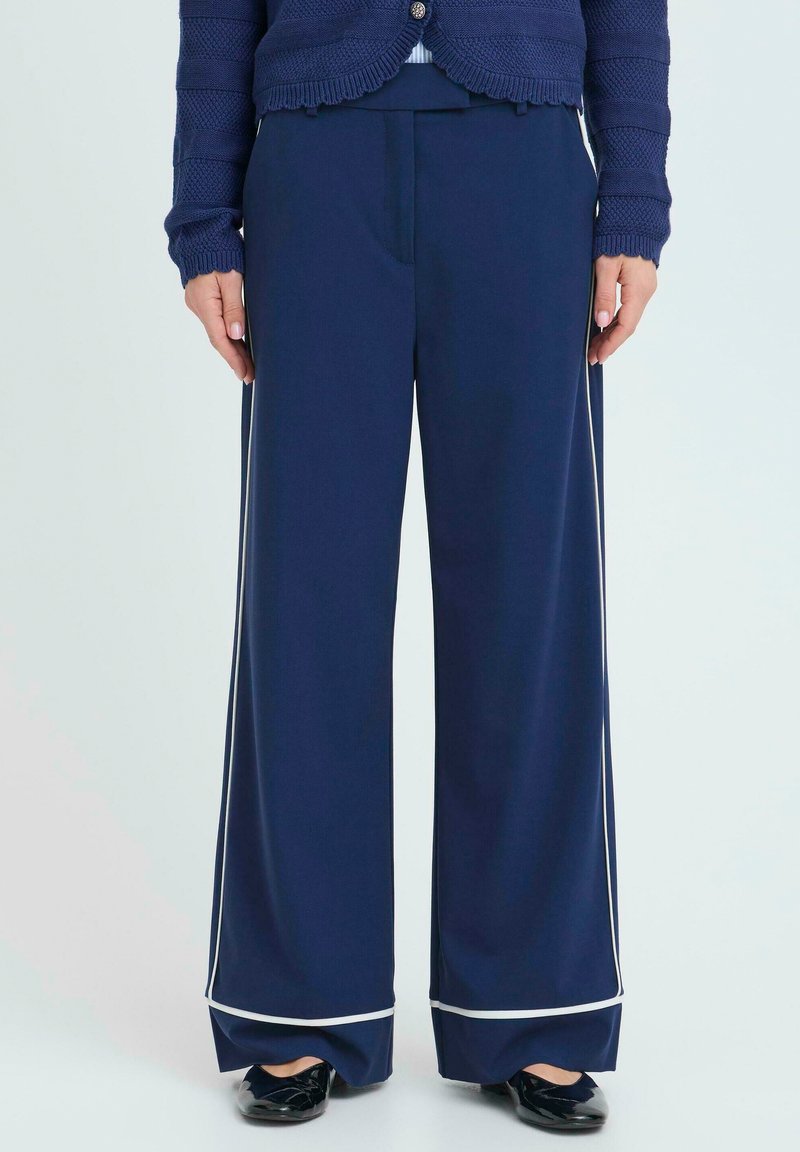 Námořnické široké kalhoty vyrobené z hladké látky, s bílým lemováním na okraji, podrobně zpracovanými předními sklady a pohodlným pasem.