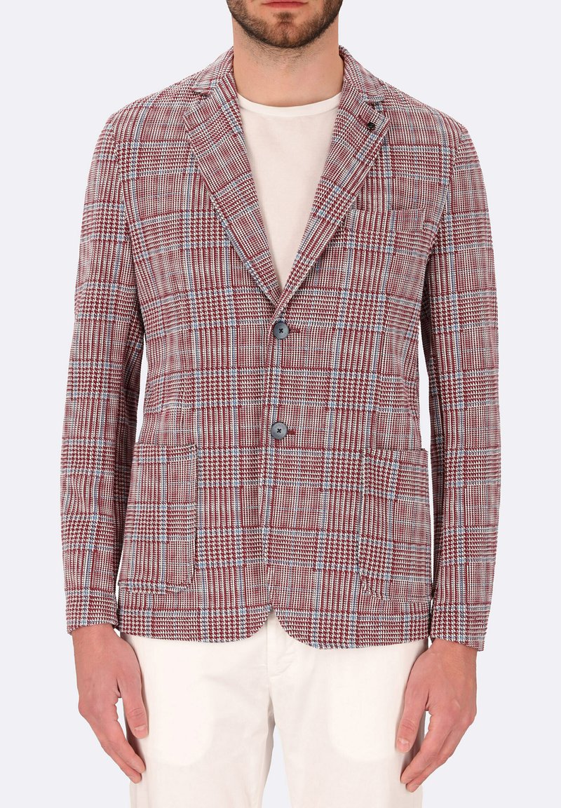 Blazer a quadri rosso e blu con rever a punta, due bottoni, tasche frontali e un tessuto texturizzato. Indossato sopra una maglietta chiara.