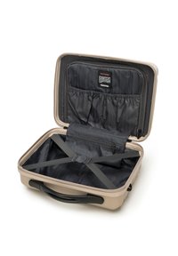 Valigia rigida beige con interno in tessuto nero, tasche con zip e cinghie elastiche per garantire la sicurezza del contenuto, dotata di manico liscio.