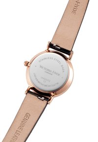 Prawdziwy skórzany pasek, tylny wieczko ze stali nierdzewnej w kolorze różowego złota, biała tarcza, grawerowane logo marki oraz wskaźnik wodoodporności.
