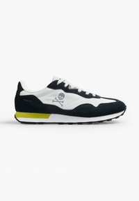 Sneakers con una toma superiore in rete bianca, accenti in suede blu navy, logo a testa di morto e dettaglio giallo sul tallone. Suola in gomma con motivo di battistrada nero.