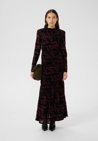 Samt, bodenlanges Kleid mit langen Ärmeln in einem dunklen lila und schwarzen Blumenmuster; verfügt über geraffte Details und einen ausgestellten Rock.