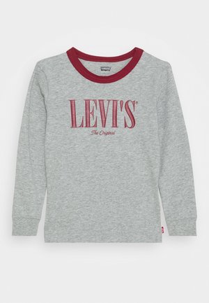 Šedé tričko s dlouhým rukávem a červeným kulatým výstřihem. Obsahuje nápis „LEVI'S“ tučnýma bordó písmeny a „The Original“ menším textem pod ním.