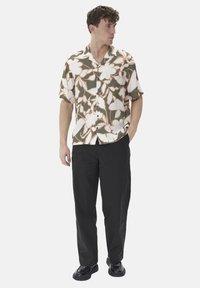 Short-sleeve shirt in cream with large floral pattern in white and brown; paired with black pants and black shoes, featuring a relaxed fit.