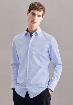 Chemise bleu clair à manches longues, avec un col classique et un motif texturé. Équipée de boutons blancs et d'un ourlet arrondi.