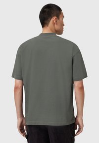 Camiseta de manga corta y cuello redondo en tela de algodón verde oscuro. Corte relajado con dobladillo recto y detalles de costura mínimos.