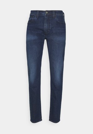 Jean en denim bleu foncé avec coupe droite, conception à cinq poches, coutures apparentes et fermeture par bouton à la taille.