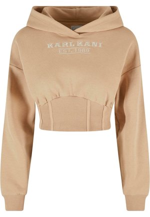 Lyhyt beige huppari, joka on valmistettu pehmeästä kankaasta, jossa on ribbauspinnat. Varustettu hupulla ja etupuolella on kirjonta, jossa lukee "KARL KANI EST. 1989."