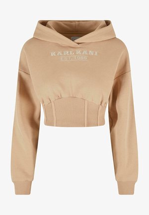 Izgriezts bēšs kapuce ar mīkstu audumu un ribotām detaļām. Ar cape un priekšējo izšuvumu ar tekstu "KARL KANI EST. 1989."