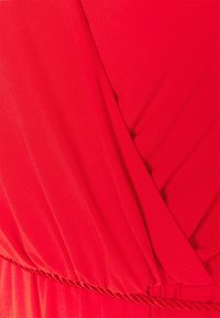 Nahaufnahme eines roten Stoffes mit Wickeldesign und geraffter elastischer Naht.