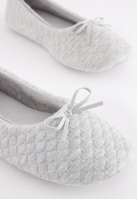 Graue Ballerinas aus strukturiertem Stoff mit Rautenmuster, abgerundetem Zehenbereich und einer dekorativen Schleife vorne. Weiches Innenfutter.
