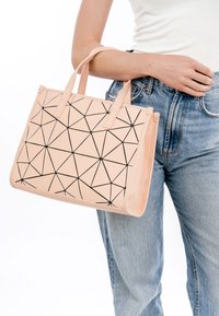 Różowa geometryczna torba tote z czarnym trójkątnym wzorem. Wykonana z gładkiego materiału, z podwójnymi uchwytami na górze i strukturalnym kształtem.