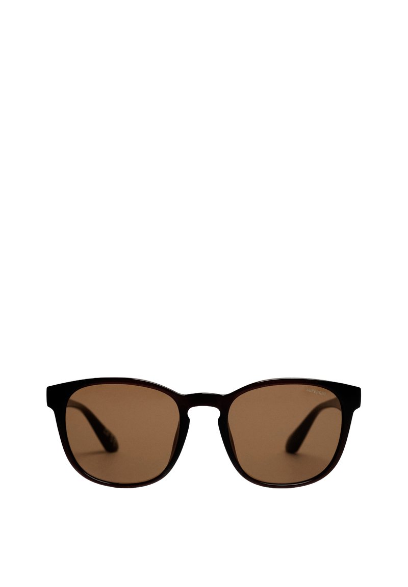 Gafas de sol rectangulares negras con lentes marrones, con montura ligeramente curva y patillas delgadas. El logotipo de la marca está sutilmente colocado en el lente.
