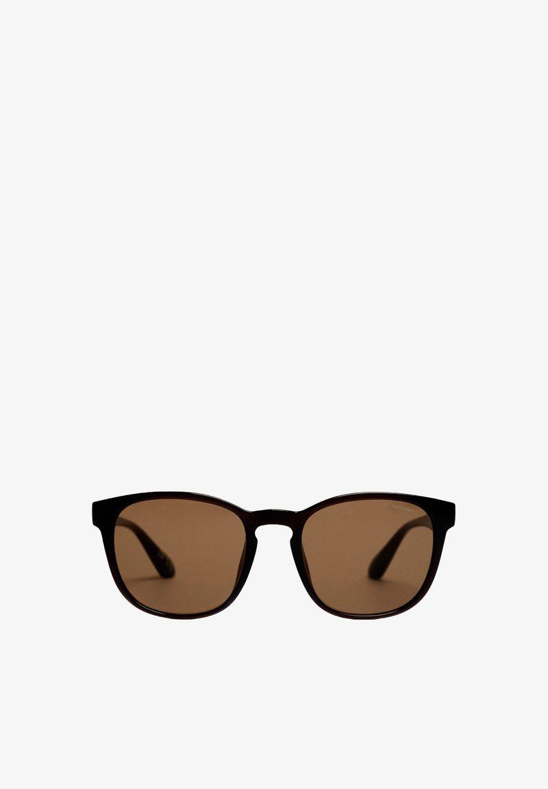 Gafas de sol rectangulares negras con lentes marrones, con montura ligeramente curva y patillas delgadas. El logotipo de la marca está sutilmente colocado en el lente.