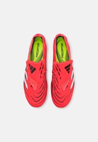 Felrood atletiekschoenen met geventileerd ontwerp, voorzien van zwart-witte strepen en een groene binnenzool met het label "PREDATOR."