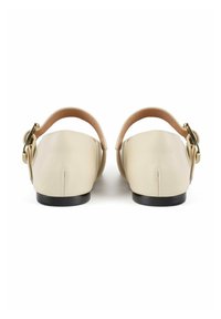 Chaussures beige sans dos avec une finition en cuir lisse, présentant une sangle marron et des détails en métal doré. Les semelles noires complètent le design.
