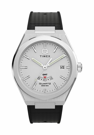 Silver Timex wristwatch with white dial, black hour markers, GMT indicator, date window, and black textured strap.